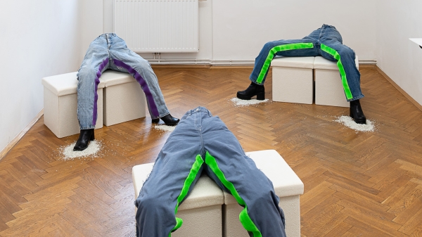 Jeanshosen mit Klettverschluss an den Innenseiten der Beinen sind auf drei Podesten
                                          angeordnet.