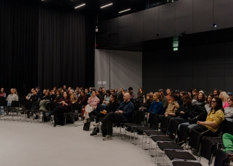 Audience sitting on chairs in an event hall listening
                                          to Richard Hawkins and Christian Liclair